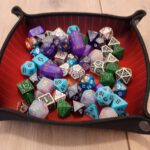 Een dicetray gevuld met een hoop dobbelstenen van allerlei soorten en formaten.