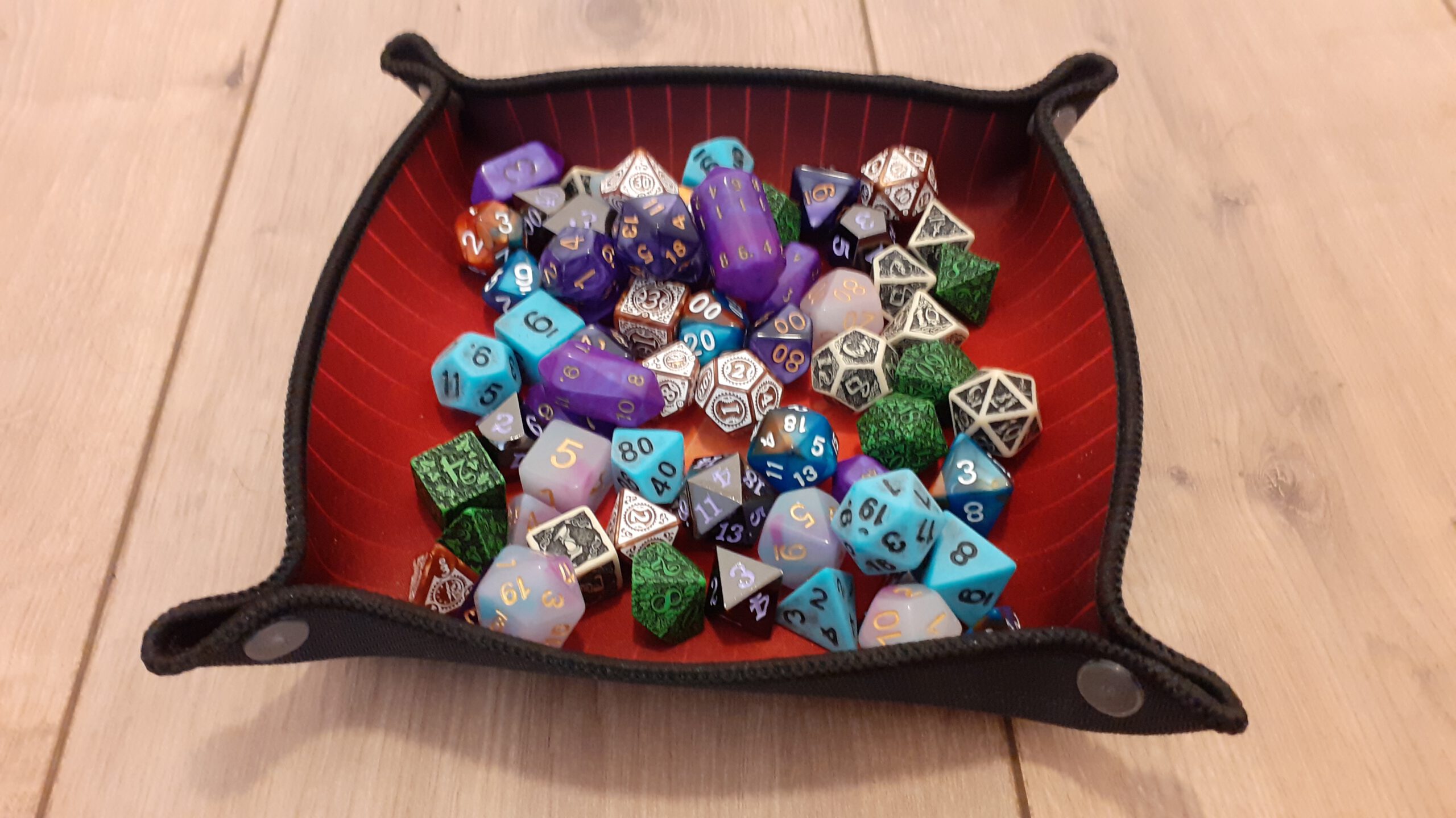 Een dicetray gevuld met een hoop dobbelstenen van allerlei soorten en formaten.