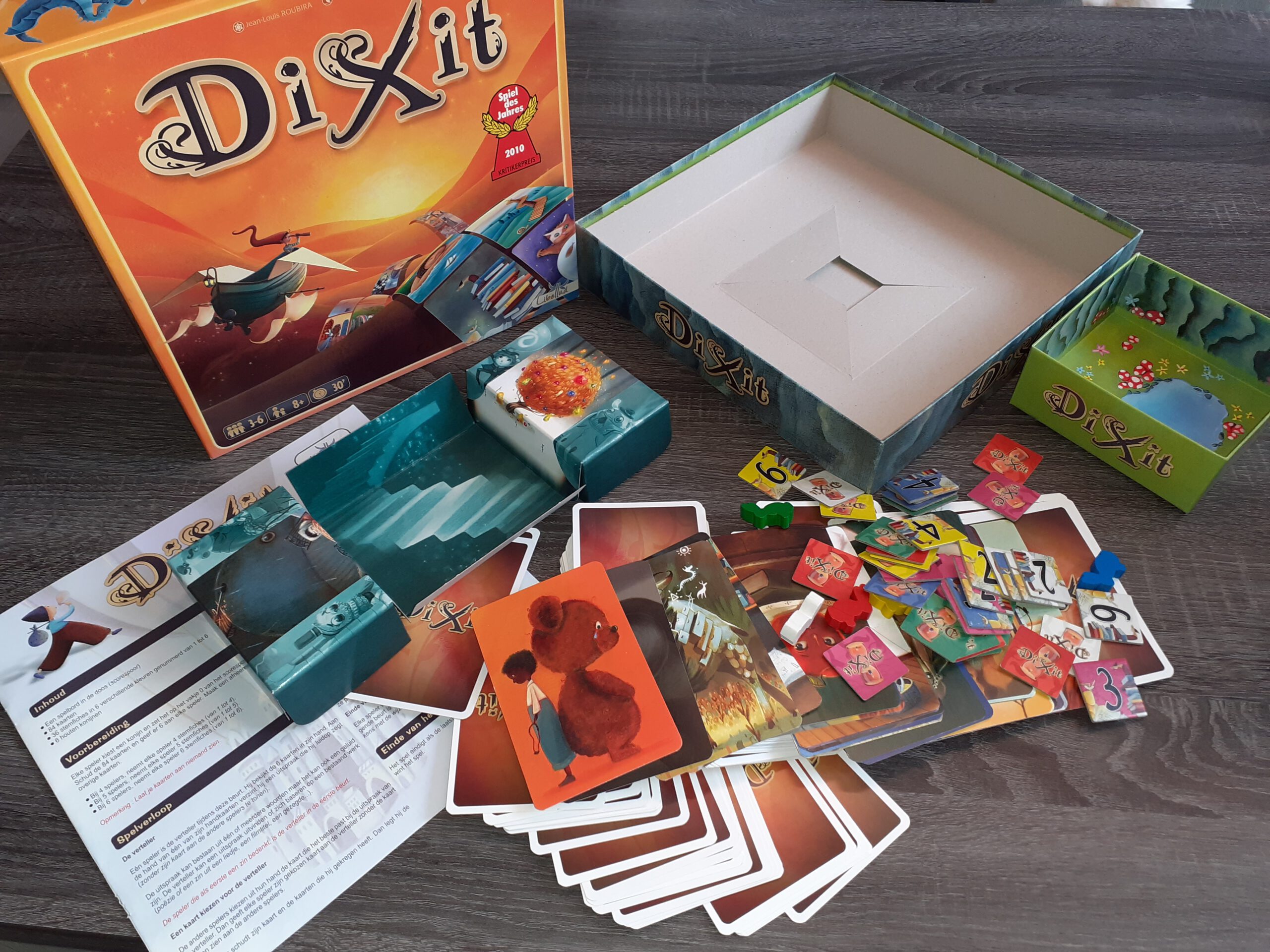 De doos en inhoud van Dixit Odyssey, op display.