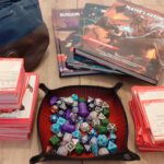 Een dice tray vol dobbelstenen, spell- en monsterkaarten, Dungeons and Dragons handboeken en de Bailey's Bag of Holding.