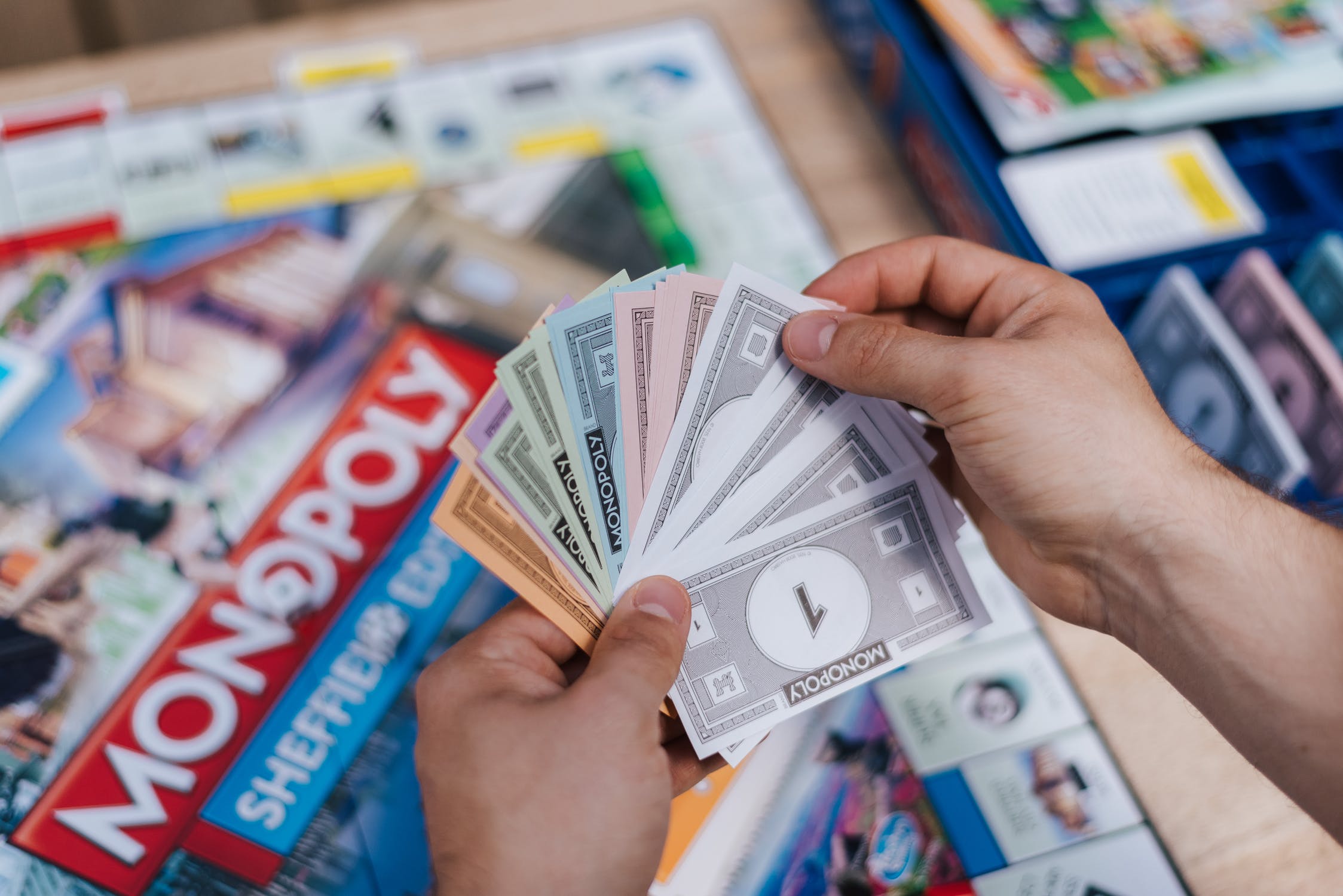 Een speler staat op het punt een betaling te maken in Monopoly, met een waaier van geld op handen.