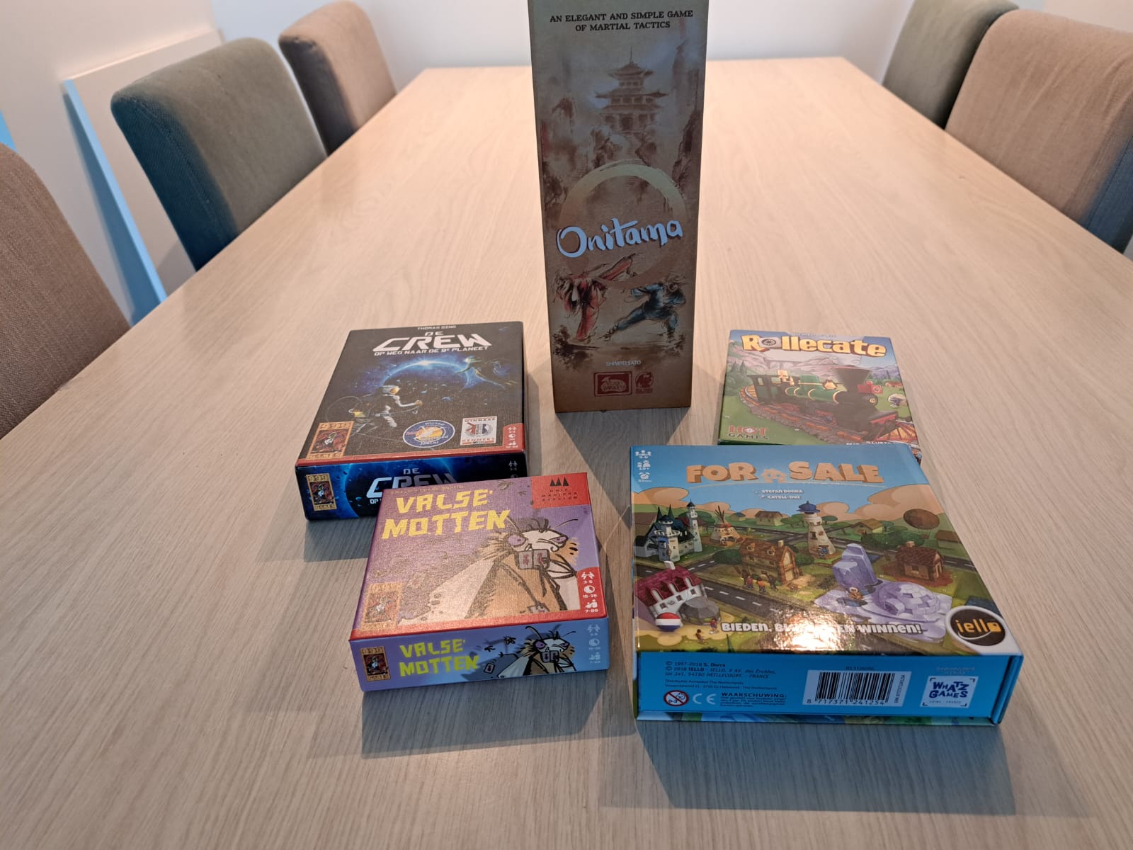 Vijf korte bordspellen bij elkaar op een tafel. In beeld zijn Onitama, De Crew, On Sale, Valse Motten en Rollecate.