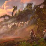 Een screenshot van Horizon: Forbidden West DLC Burning Shores. Aloy en Seyka lopen langs het vernietigde Hollywoodbord van Los Angeles.