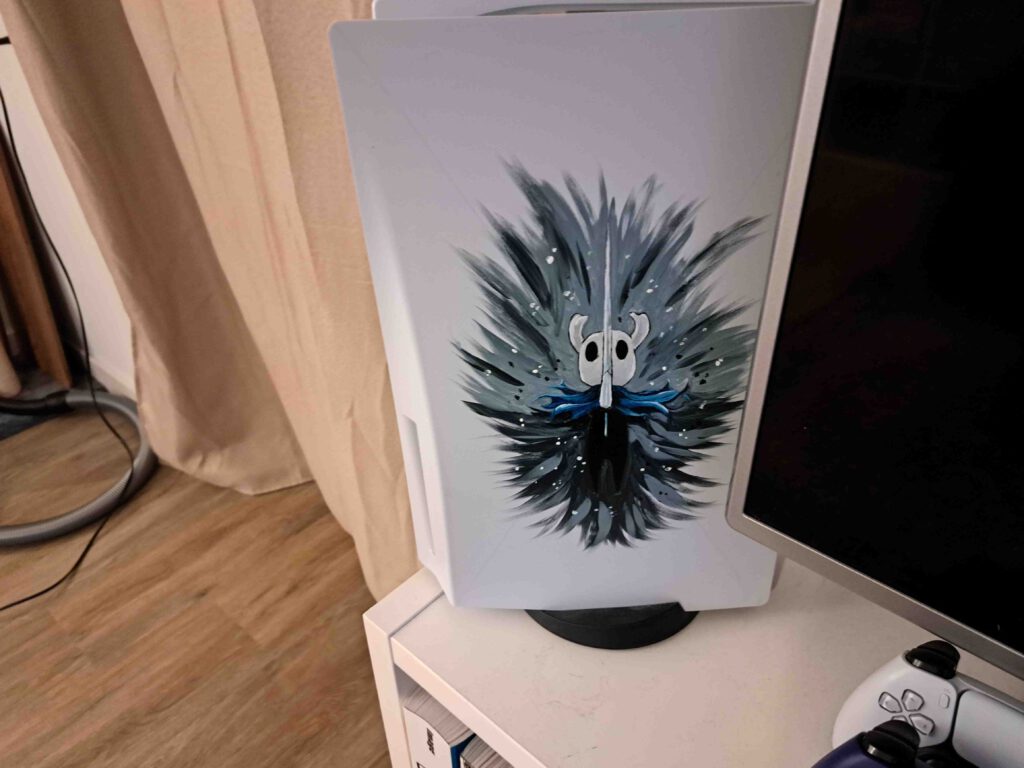 Mijn PlayStation 5 opgesteld naast de TV. De dappere Hollow Knight waakt over mijn games.