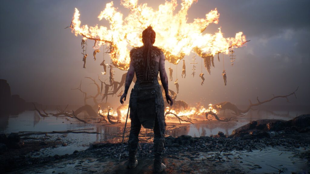 Senua staat voor een brandende boom. Een screenshot uit Hellblade: Senua's Sacrifice.
